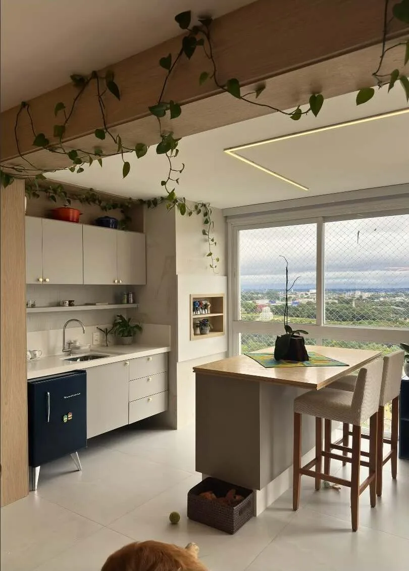 Cozinha integrada com ilha, armários planejados e iluminação linear